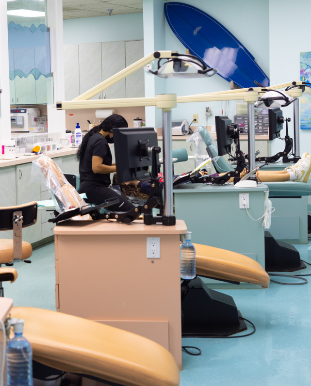 Orthodontist examining patient in modern dental treatment room with equipment and blue décor.